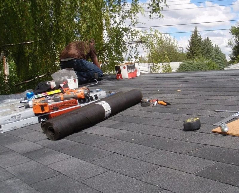 Монтажник чинит крышу многоквартирного дома